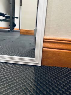 an empty gym room with a mirror on the floor and exercise equipment in the background