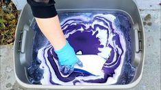 a person in blue gloves is cleaning the floor with purple and white paint on it