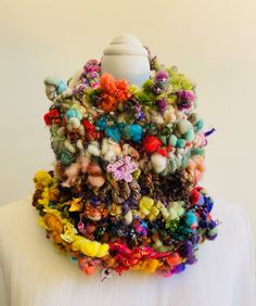 a white mannequin is covered in multicolored yarn