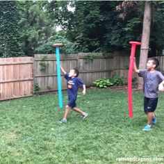 two young boys playing in the yard with frisbees and plastic hoop holders