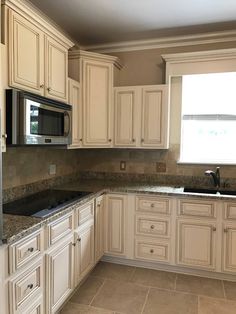 an empty kitchen with white cabinets and granite counter tops is seen in this image from the front view