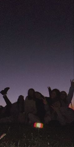 a group of people sitting in the grass at night