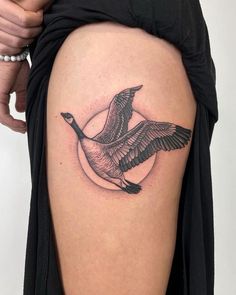 a woman's thigh with a tattoo of a bird flying in front of her