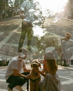 two people and a dog are sitting on the sidewalk with their reflection in the window