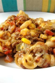 a white plate topped with macaroni and cheese covered in ground beef next to a fork