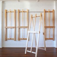 an easel leaning against the wall in front of three wooden shelves with ladders on them