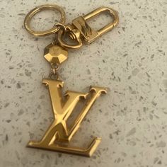 a gold keychain with the letter l on it's front and back ends