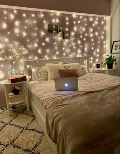 a bed room with a laptop computer on top of it and lights all over the wall