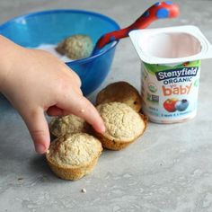 a hand reaching for some biscuits next to a bowl of yogurt