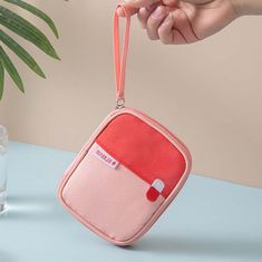 a pink and red purse sitting on top of a table next to a glass filled with water