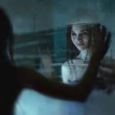 a woman standing in front of a mirror with her reflection