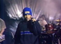 a man with a blue hat is on the phone and holding a drum set in front of him