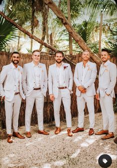 a group of men standing next to each other wearing white suits and orange bow ties