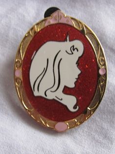 a red and gold brooch with a white unicorn on it's back side