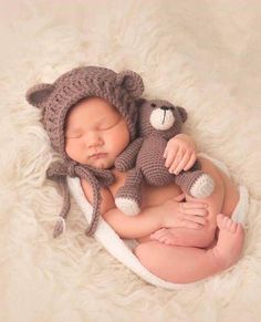 a newborn baby wearing a bear hat and holding a teddy bear