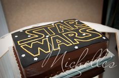 a star wars cake with chocolate frosting and stars on the top is sitting on a chair