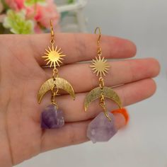 ♡ Raw Amethyst Solar Star Sun Mismatched Earrings ♡ Our Large Crystal Purple Stone Earrings Are A Meaningful And Symbolic Gift. Show Some Well Deserved Love To Yourself And Loved Ones With These Gemstone Earrings. The Elegance Of The Gold Rising Sun Is Gorgeously Complemented By The Beauty The Dangling Purple Crystals. Size: 3.6 inch long, 1 inch wide W H Y ∙ Y O U ' L L ∙ L O V E ∙ I T • They are beautiful dangle earrings that can be worn every day with any outfit • A special piece you will che Celestial Amethyst Gold Jewelry, Handmade Purple Celestial Earrings, Celestial Purple Dangle Earrings, Purple Celestial Dangle Earrings, Purple Crystal Metal Earrings For Gifts, Purple Metal Crystal Earrings As Gift, Purple Metal Crystal Earrings For Gift, Handmade Amethyst Crystal Earrings In Gold, Celestial Crystal Pierced Earrings For Gift