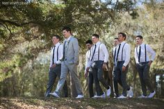 a group of men in suits and ties walking down a hill with trees behind them