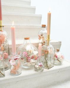 several glass vases with flowers and candles in them on a ledge next to stairs