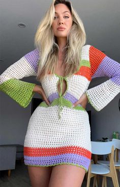 a woman in a colorful crochet dress posing for the camera