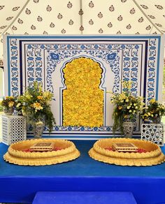 two pies sitting on top of a blue table under a white and yellow tent