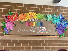 a bulletin board with flowers on it in front of a brick wall that says, you are beautiful when you grow