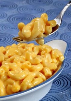 a spoon full of macaroni and cheese on top of a blue tablecloth