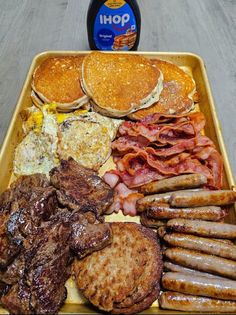 a tray filled with pancakes, sausages and bacon