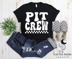 a t - shirt that says pit crew on it next to some jeans and shoes