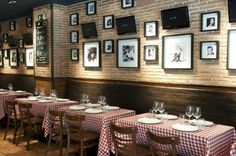 a restaurant with tables and chairs covered in checkered tablecloths, framed pictures on the wall