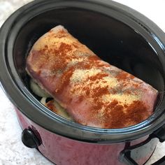 a large piece of meat in a crock pot on the counter top with some seasoning