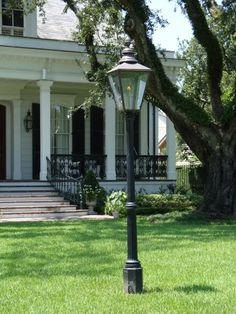 a lamp post in front of a large white house with columns on the porch and steps leading up to it