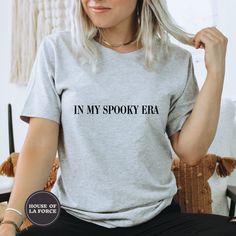 "\"In My Spooky Era\" Funny Halloween Eras Adult Shirt :: GARMENT INFO :: - 100% Soft cotton (fibre content may vary for different colors) - The sleeves are rolled up for display purposes only :: SIZING :: - The Unisex sizing makes the shirt run larger than your average t-shirt (for women). We suggest ordering a size smaller than what you would normally wear. The shirts run true to size for men. - Please check out our size chart for measurements to ensure an accurate fit - No exchanges/returns f Grunge Tops With Text Print For Halloween, Grunge Text Print Top For Halloween, Grunge Style Text Print Tops For Halloween, Trendy Halloween Tops With Text Print, Movie Lover Gift, Geek Shirts, Goth Shirt, Horror Lovers, Oversized Graphic Tee