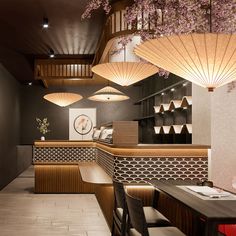 the interior of a japanese restaurant with wooden tables and stools, hanging lights above