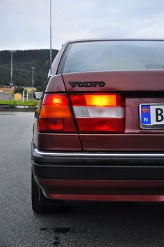 a red car parked in a parking lot next to another car with the number b on it's license plate