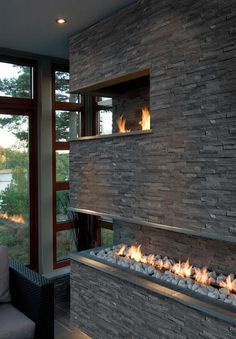 a fire place in the middle of a living room next to a couch and window