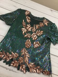 Women's Razzle Dazzle Green/Gold Sequin & Silk Short Sleeve Blouse *No size tag*. See measurements photos. Item is in used condition. Shipped with USPS Shipping. Green Tops For Evening Party Season, Green Sequin Tops For Fall, Green Sequined Short Sleeve Tops, Green Sequined Party Blouse, Festive Green Sequined Tops, Festive Green Sequin Tops, Green Sequined Blouse For Evening, Green Embellished Festive Tops, Fall Sequined Short Sleeve Blouse