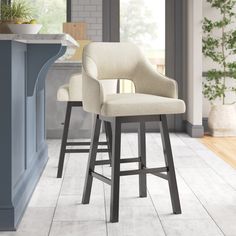 two beige bar stools in front of a kitchen island with potted plants on it