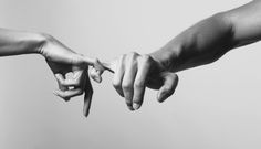 black and white photograph of two hands reaching out to touch each other's fingers