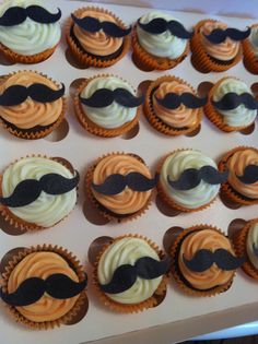 cupcakes with white frosting and black mustaches on them in a box