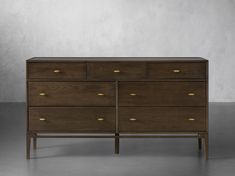 a wooden dresser with brass handles and drawers on it's sides, against a white wall