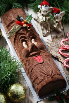 a long piece of chocolate cake sitting on top of a table next to christmas decorations