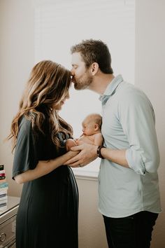 a man and woman are holding a baby in their arms as they look at each other