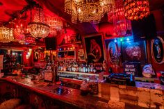 a dimly lit bar with chandeliers hanging from the ceiling and pictures on the walls