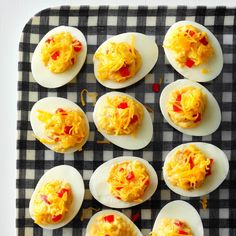 an assortment of deviled eggs on a black and white checkered tray