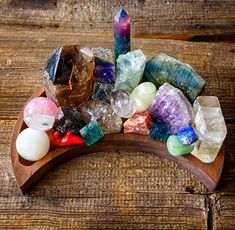 a wooden tray filled with different colored rocks and crystals on top of a wooden table