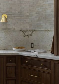 a kitchen with marble counter tops and wooden cabinets, along with a gold light fixture