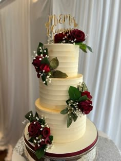 a three tiered wedding cake with red roses on the side and mr and mrs written on top