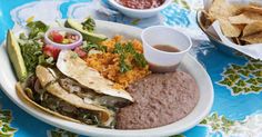 a white plate topped with lots of food next to bowls of salsa and tortillas