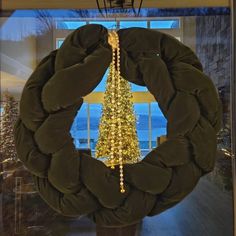 a wreath with lights hanging from it in front of a window